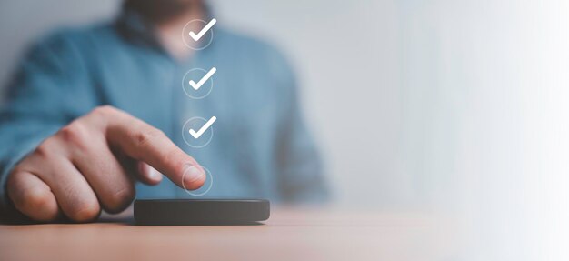 Businessman touching to screen of smartphone to tick correct mark to approve document and project concept