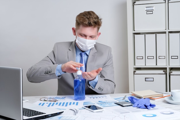 Businessman treats his hands with antibacterial gel in the workplace.