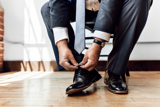 Foto uomo d'affari che allaccia i lacci delle scarpe prima di andare al lavoro