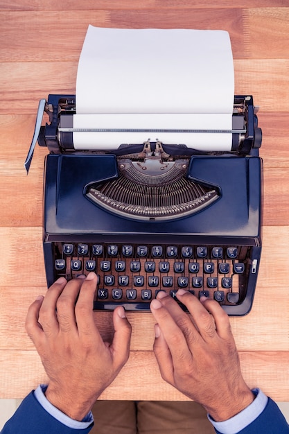 Uomo d'affari che scrive sulla macchina da scrivere allo scrittorio di legno in ufficio