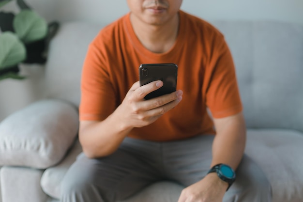 A businessman uses his smartphone while sitting on his sofa at home Concept of young people working on mobile devices