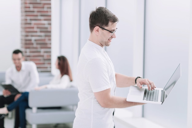 Businessman uses laptop while standing in office. people and technology