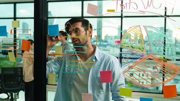 Photo businessman uses sticky notes at glass wall to brainstorming idea tracery