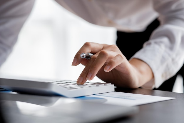 Businessman using a calculator to calculate numbers on a\
company\'s financial documents he is analyzing historical financial\
data to plan how to grow the company financial concept