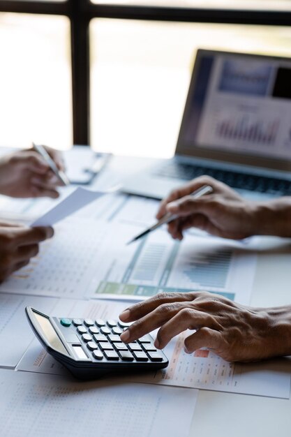 Businessman using a calculator to calculate numbers on a company's financial documents he is analyzing historical financial data to plan how to grow the company Financial concept