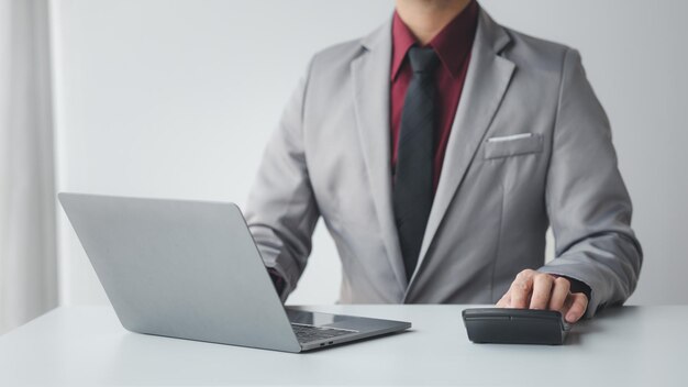 Businessman using a calculator to calculate numbers on a company's financial documents she is analyzing historical financial data to plan how to grow the company Financial concept