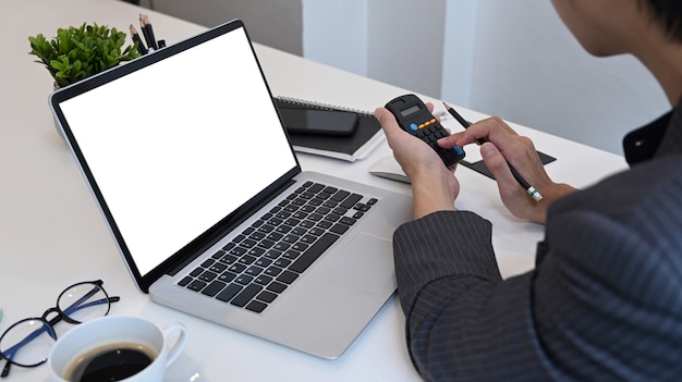 Businessman using calculator and working with laptop at office.