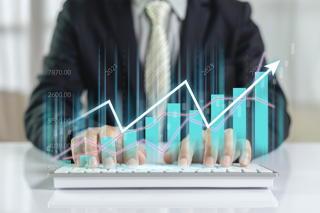 Photo businessman using computer keyboard with trading graph, âstock exchange marketing analyzing chart. information statistics diagram profit. investment and marketing concept.