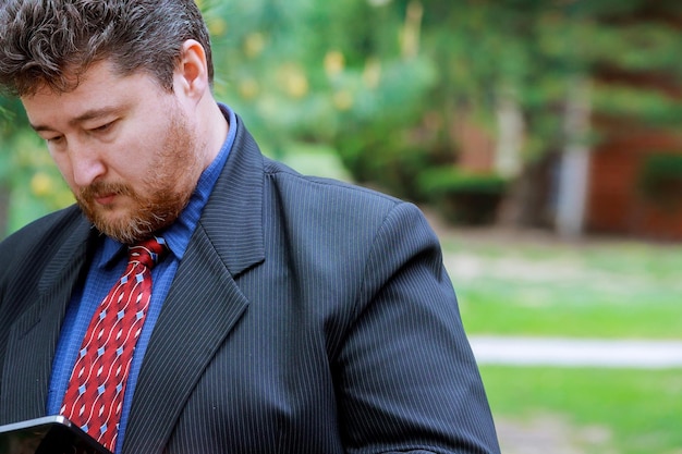 Photo businessman using digital table while standing at park