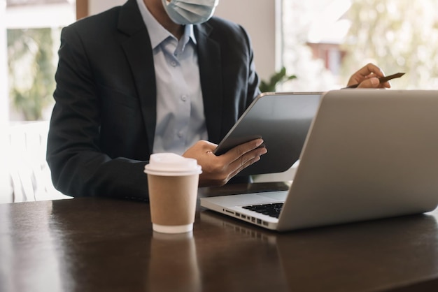 Businessman using digital tablet analyzes business data busy working on laptop computer with tablet and business report on office desk business strategy analysis concept