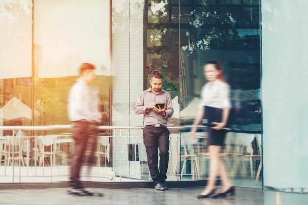 Businessman using a digital tablet office outdoors and Blurred People Walking 