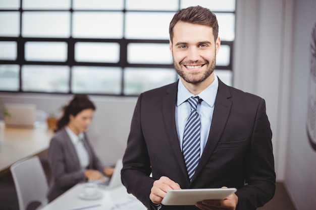 Businessman using digital tablet while colleague in background