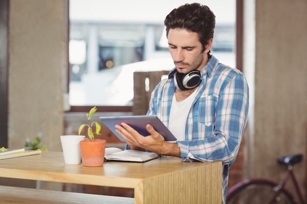 Бизнесмен, используя цифровой планшет, стоя на столе в офисе