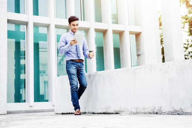 Businessman using digital tablet while walking against building