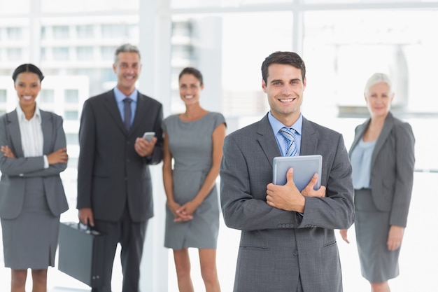 Businessman using digital tablet with colleagues behind