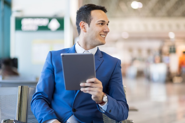 Uomo d'affari che utilizza compressa elettronica in un aeroporto