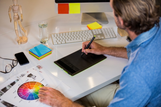 Foto uomo d'affari facendo uso della tavola dei grafici allo scrittorio