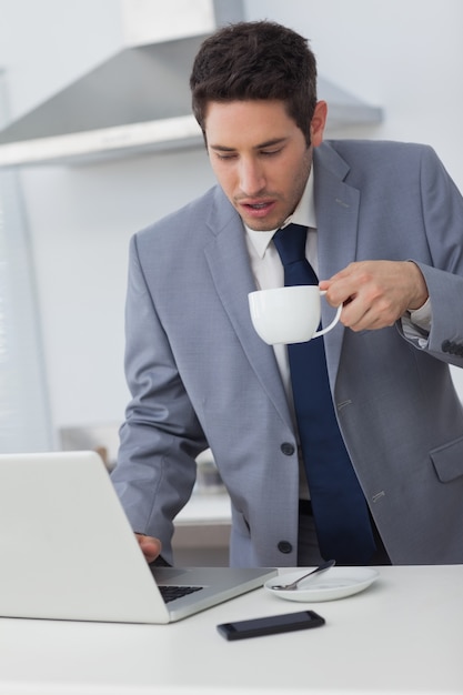 コーヒーを飲みながらラップトップを使っているビジネスマン