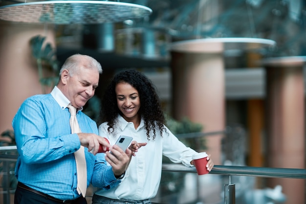 Businessman using his smartphone standing in the lobby of a busi