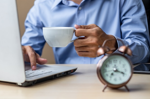 Businessman using laptop analysis marketing plan and drinking coffee 