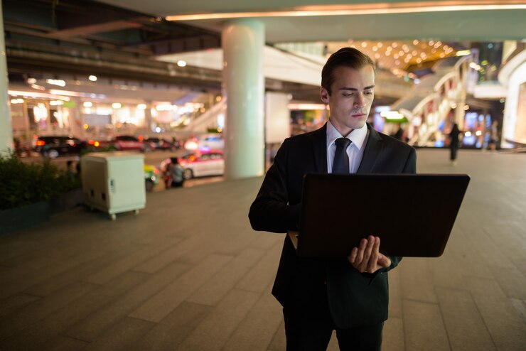Businessman using laptop computer outdoors at night in city
