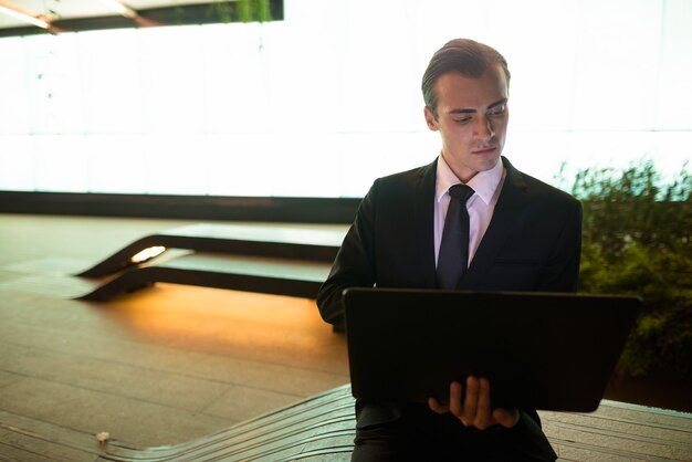 Businessman using laptop computer outdoors at night in city