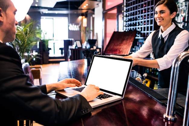 Businessman using laptop at the counter in a bar