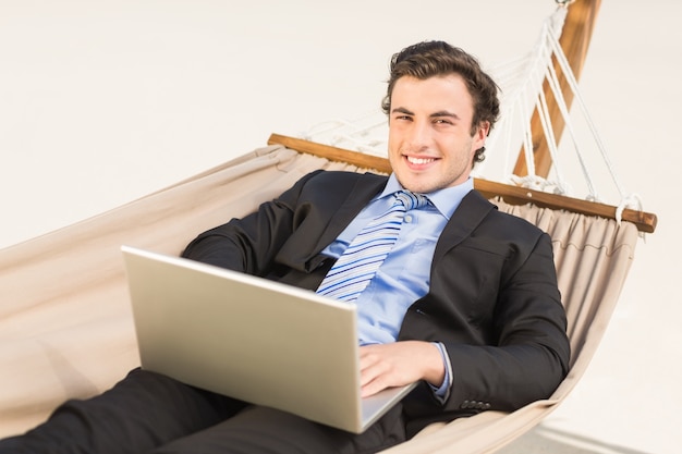 Businessman using laptop on the hammock 