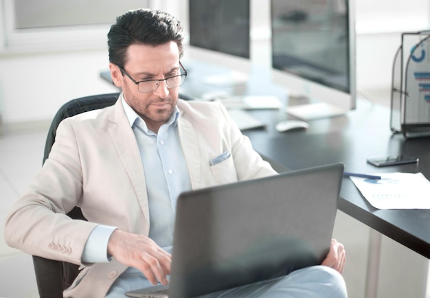 Businessman using a laptop sitting at his Desk