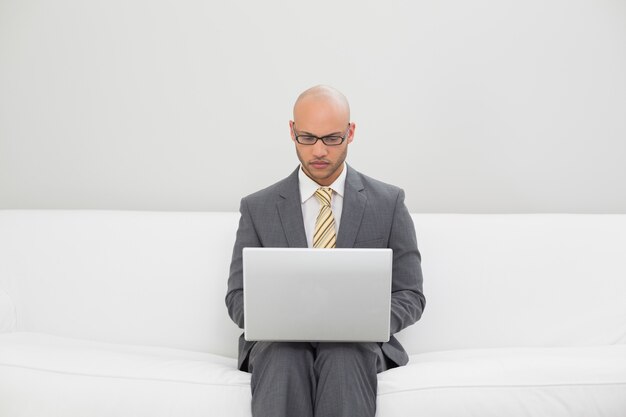 Businessman using laptop on sofa at home