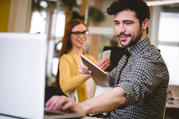 Businessman using laptop with female coworker