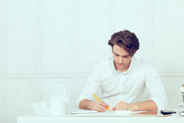 Businessman using laptop with tablet and pen