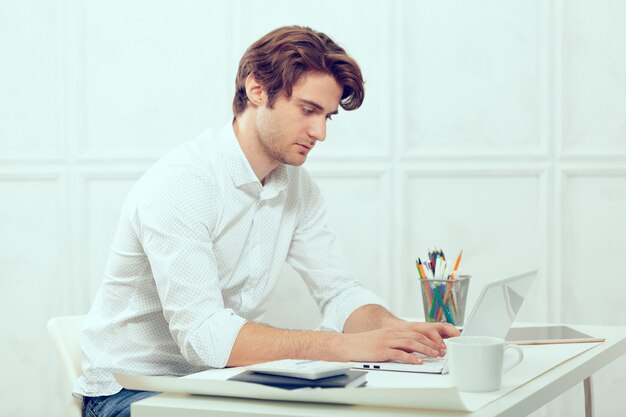 Businessman using laptop with tablet and pen