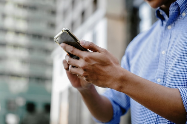 市内で携帯電話を使用するビジネスマン。トリミングされた画像、スマートフォンに焦点を当てた