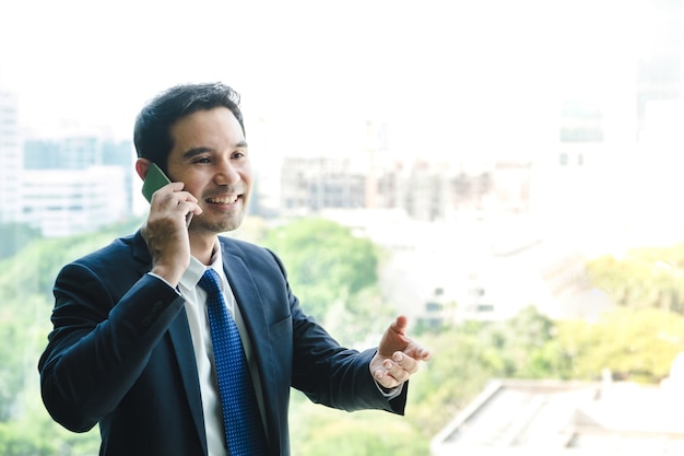 Businessman using mobile phone near office window at office 