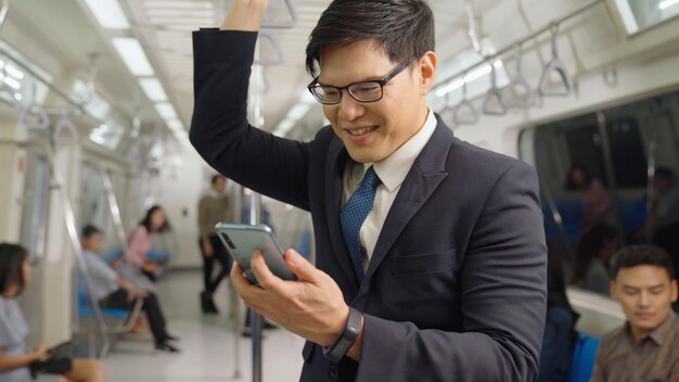 Businessman using mobile phone on public train . Urban city lifestyle commuting concept .