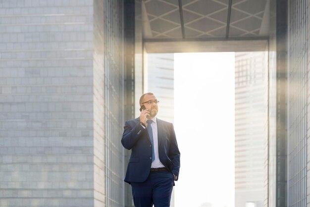 Businessman using mobile phone while standing against buildings in city