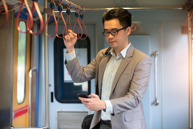 Photo businessman using mobile phone while standing in train