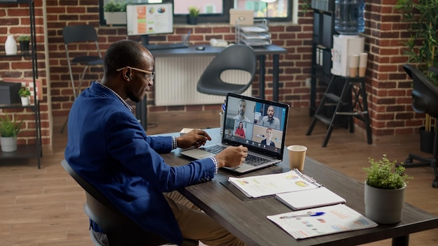 Businessman using online video call meeting with people to work\
on strategy. talking on remote videoconference for online\
conversation, internet telecommunication with webcam on\
laptop.