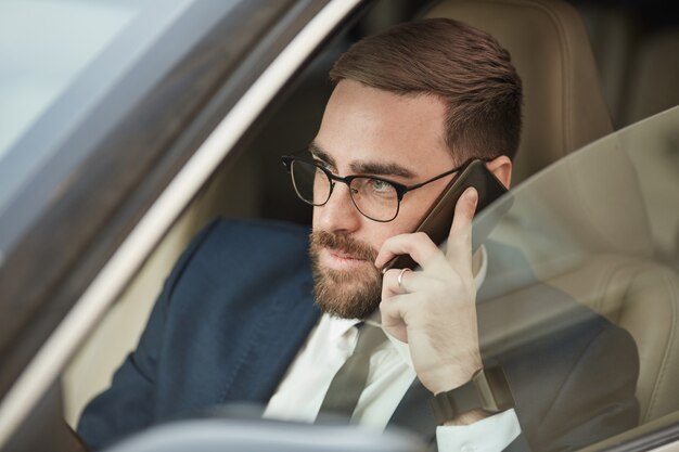 Uomo d'affari che per mezzo del telefono durante la guida