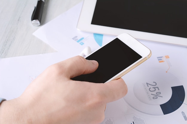 Businessman using phone with and financial papers