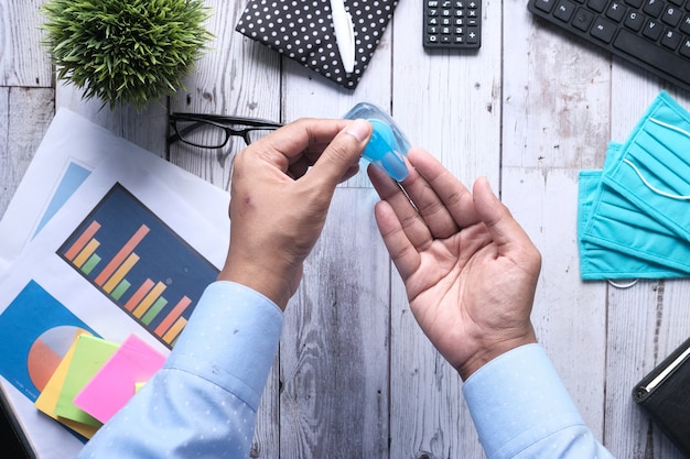 Businessman using sanitizer gel on on office desk top down