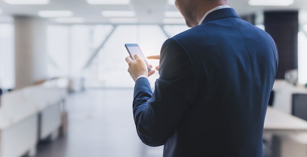 Businessman using smart phone in office space background and copy space.Concept of workplace using technology