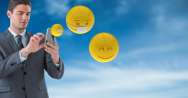 Businessman using smart phones while emojis flying against sky