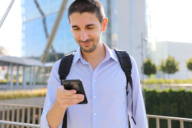 Businessman using smartphone app texting sms message in city street