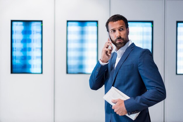 Businessman using smartphone and holding newspaper