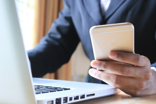 Businessman using smartphone and laptop in the office