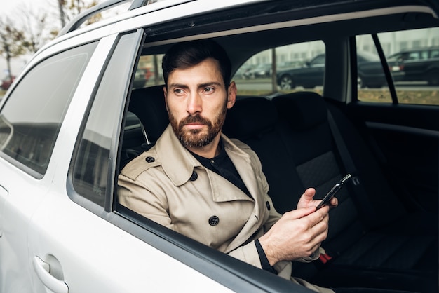 Uomo d'affari che utilizza smartphone nel taxi