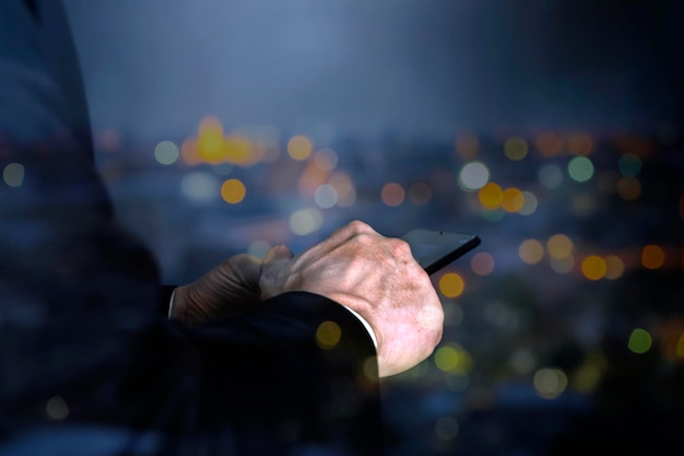 Businessman using vertical black smartphone at night Blurred traffic bokeh light