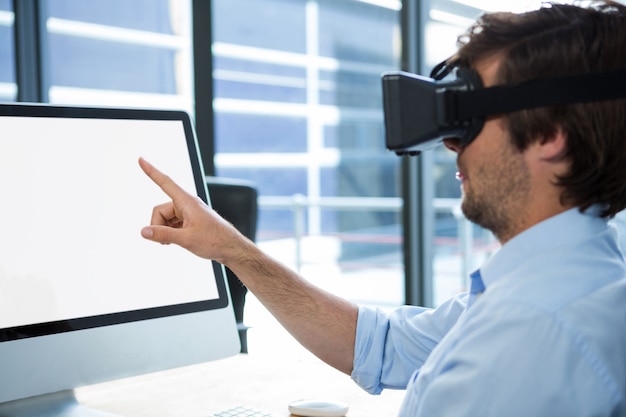 Foto uomo d'affari facendo uso della cuffia avricolare di realtà virtuale allo scrittorio
